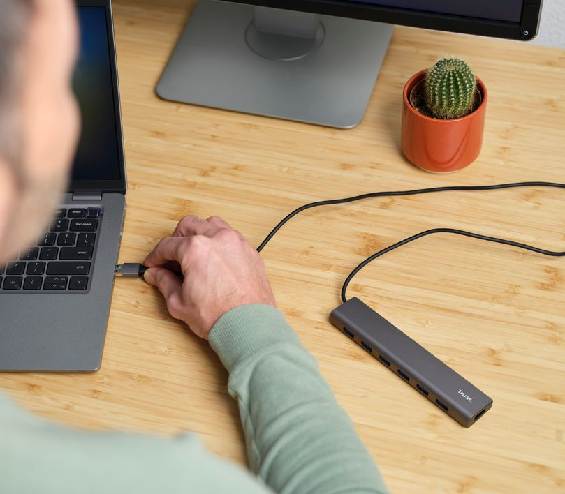 Egy személy egy USB-elosztót csatlakoztat egy laptophoz.