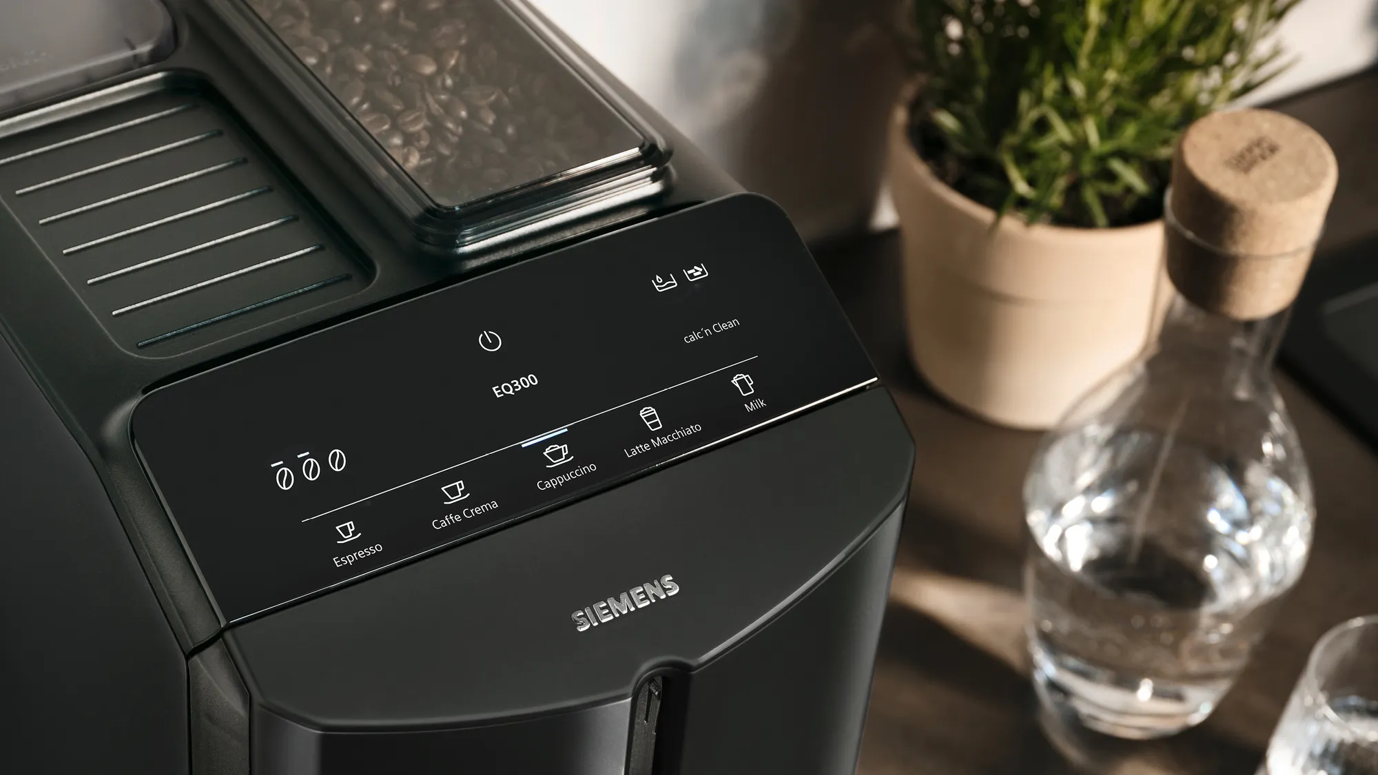 Draufsicht auf die Touch-Bedienfeld einer schwarzen Siemens EQ300 Kaffeemaschine mit Kaffeebohnenbehälter daneben.