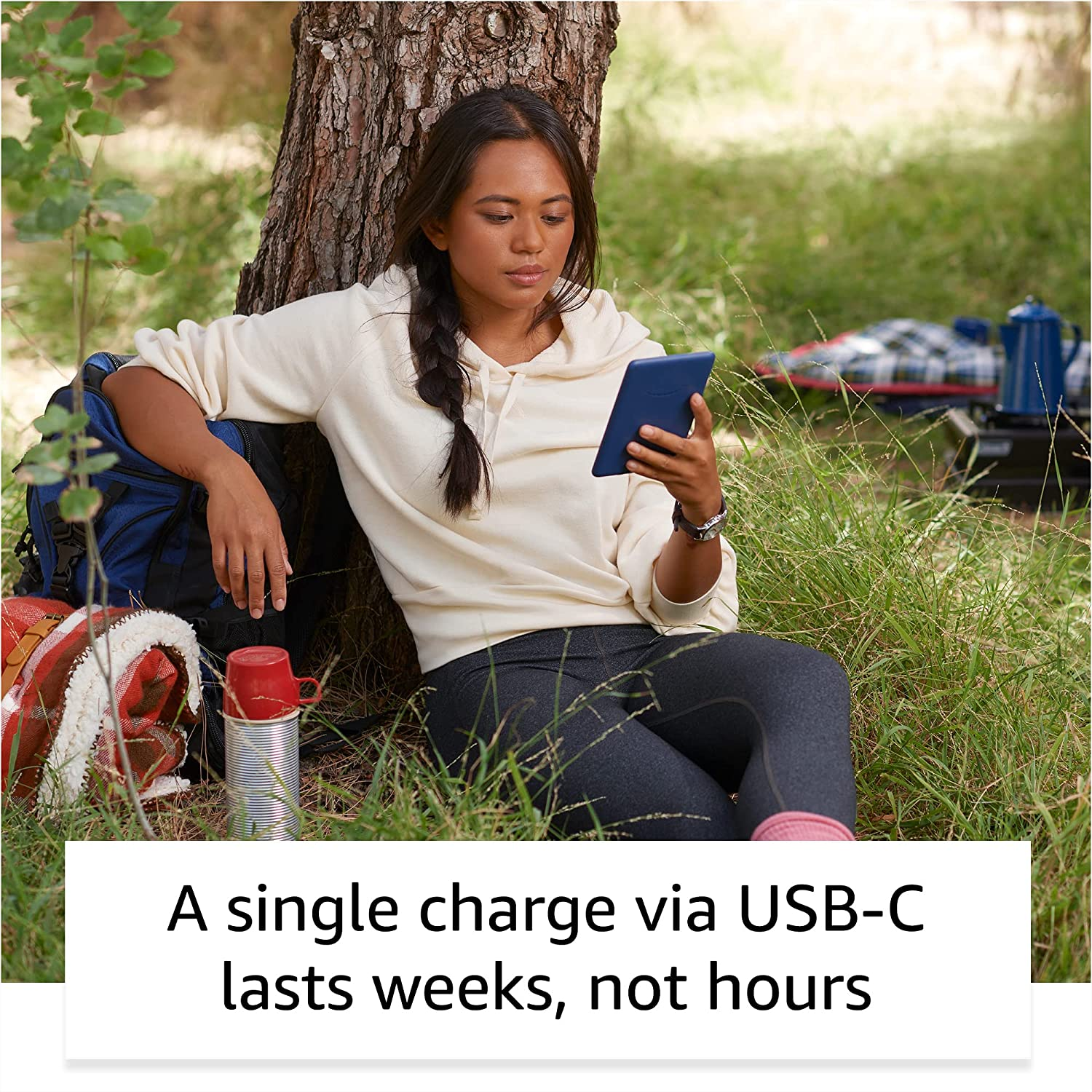 Femme lisant une tablette sous un arbre. Texte : "Une seule charge USB-C dure des semaines, pas des heures".