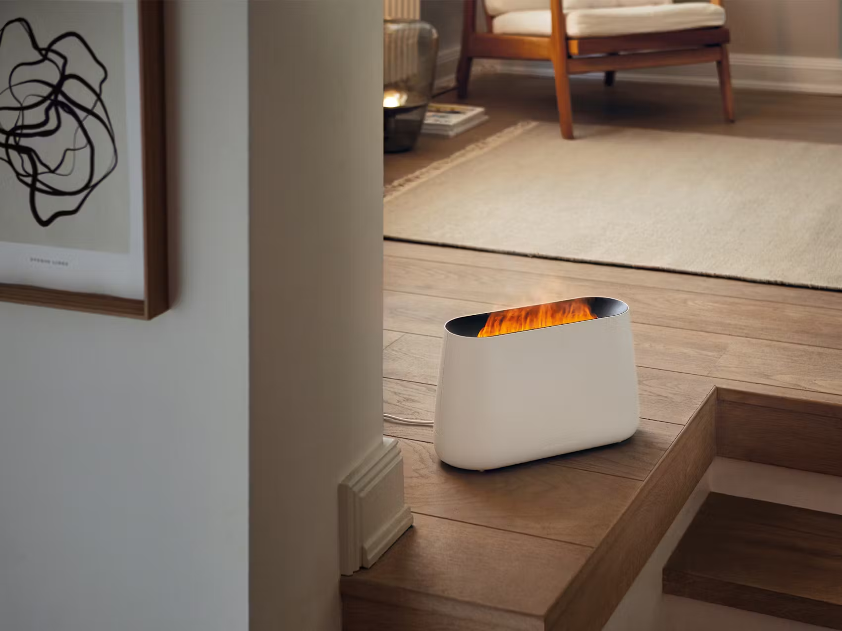 Caminetto elettrico bianco su pavimento in legno, che simula le fiamme. Un'opera incorniciata scura e un tappeto.