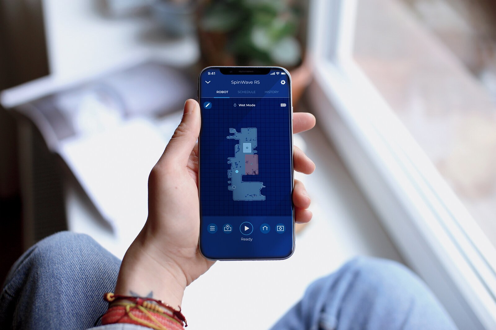 Ręka trzymająca telefon pokazuje mapę robota sprzątającego.