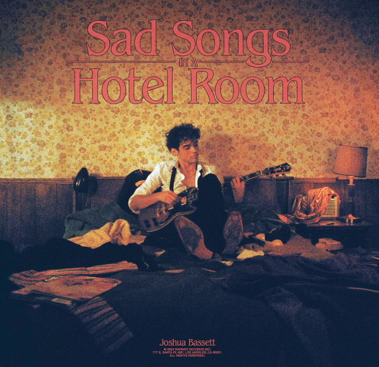Albumcover: Joshua Bassett. Sitzt in einem Hotelzimmer und spielt Gitarre. Der Titel lautet Sad Songs.