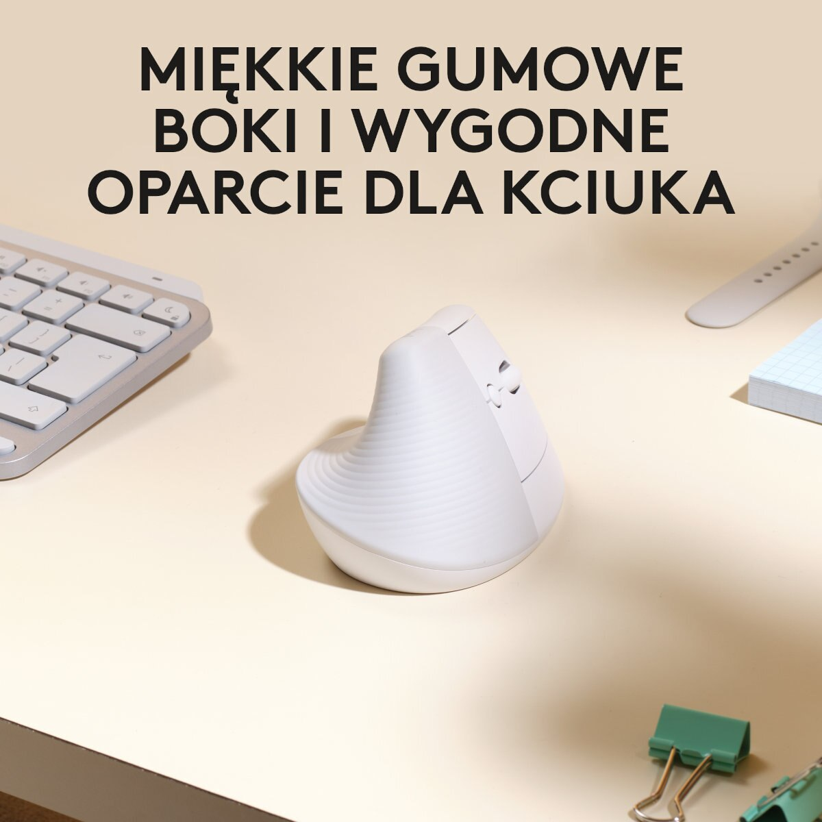 Biała ergonomiczna mysz z klawiaturą, notatnikiem i zielonym klipsem.