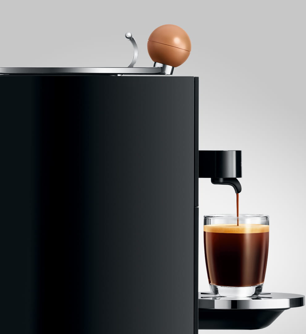 Schwarze Kaffeemaschine mit Glas, das Kaffee ausgießt. Brauner Aufsatz.
