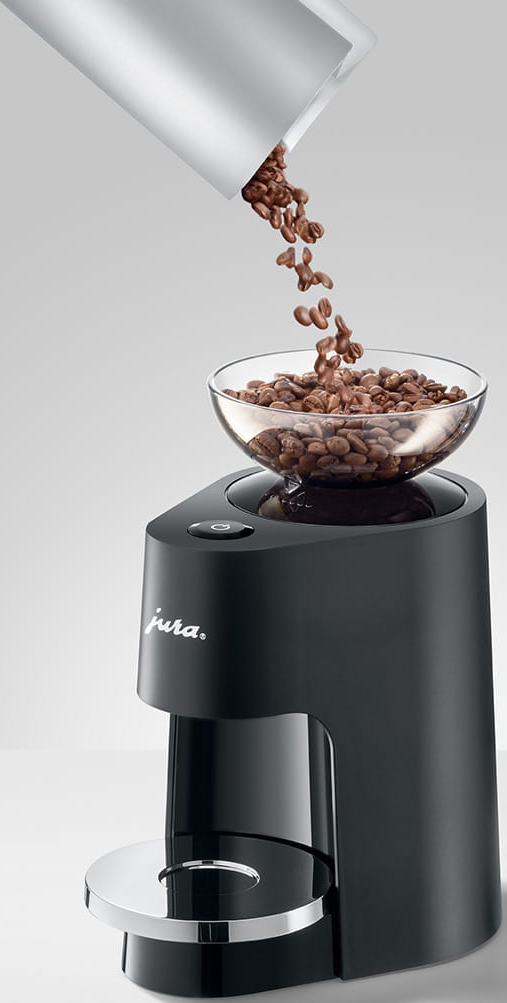 Una macchina da caffè nera con una ciotola trasparente che contiene chicchi di caffè, i chicchi vengono versati dall'alto.