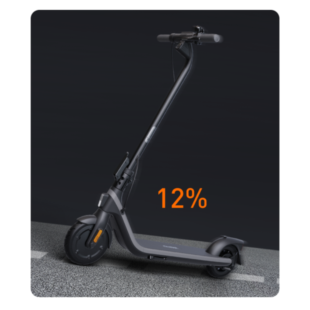 Egy fekete elektromos robogó szürke felületen, 12%-os töltésjelzővel.