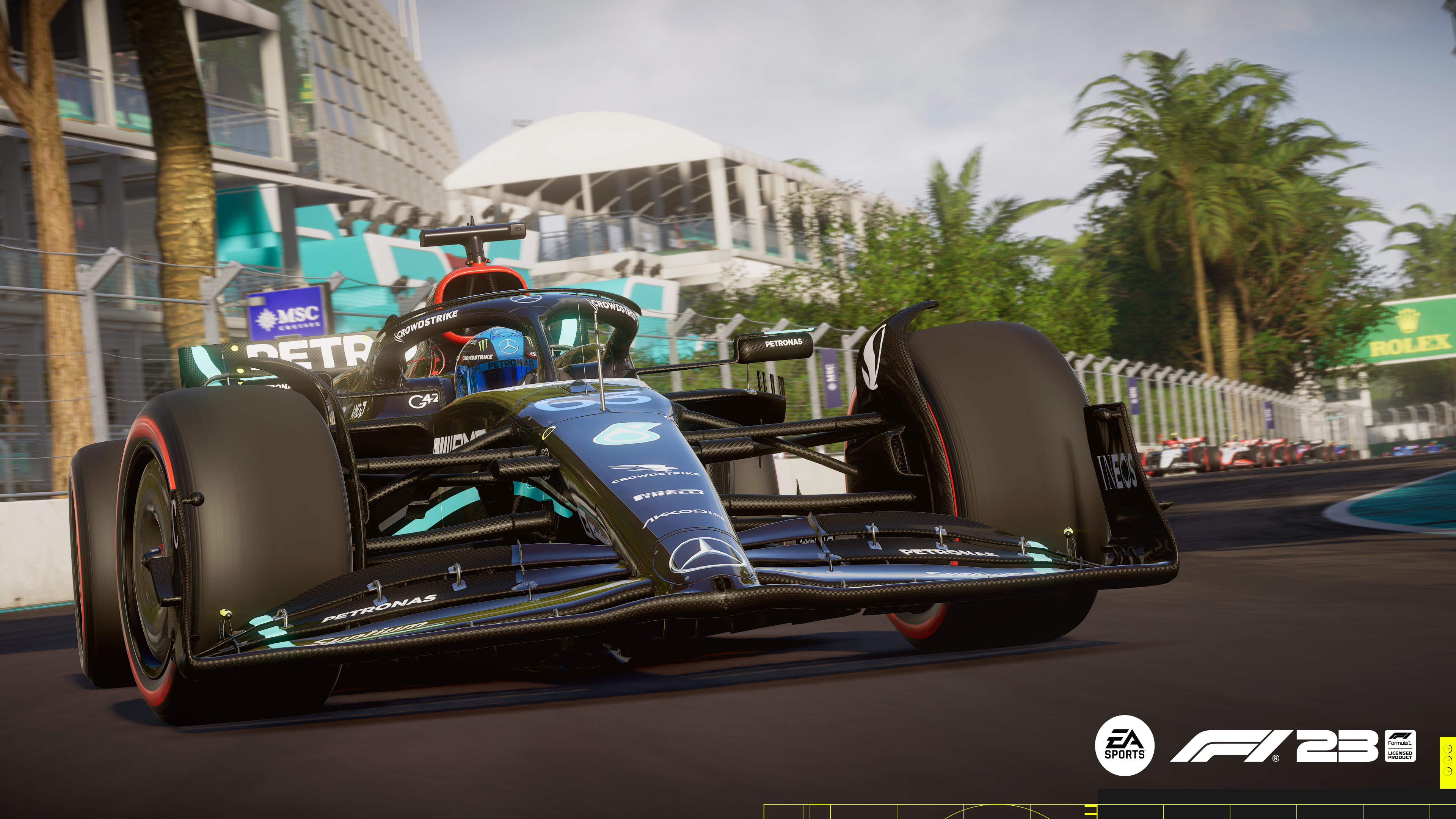 Ein schwarzes Formel-1-Auto fährt auf einer Rennstrecke mit anderen Autos und Palmen.