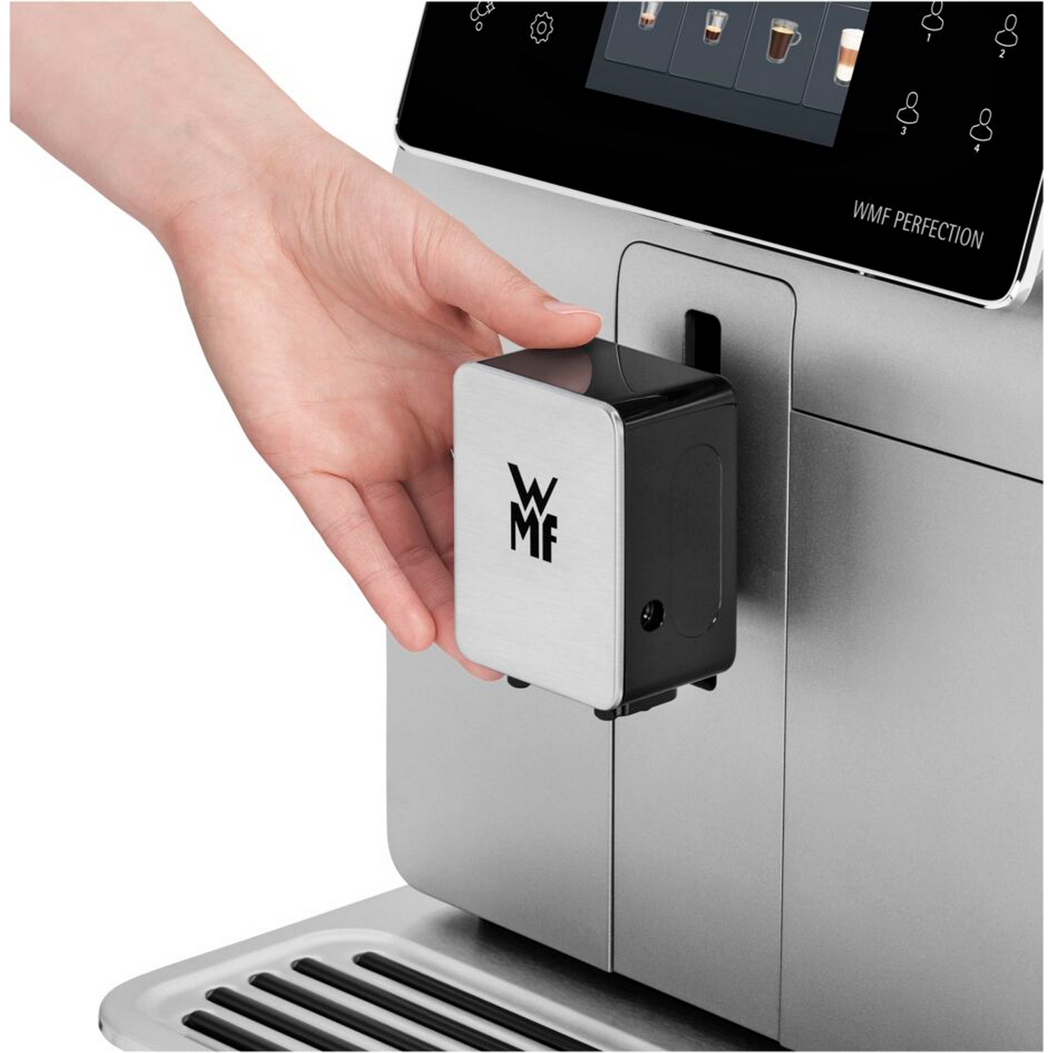 A person's hand inserts a silver object into a silver and black coffee machine.