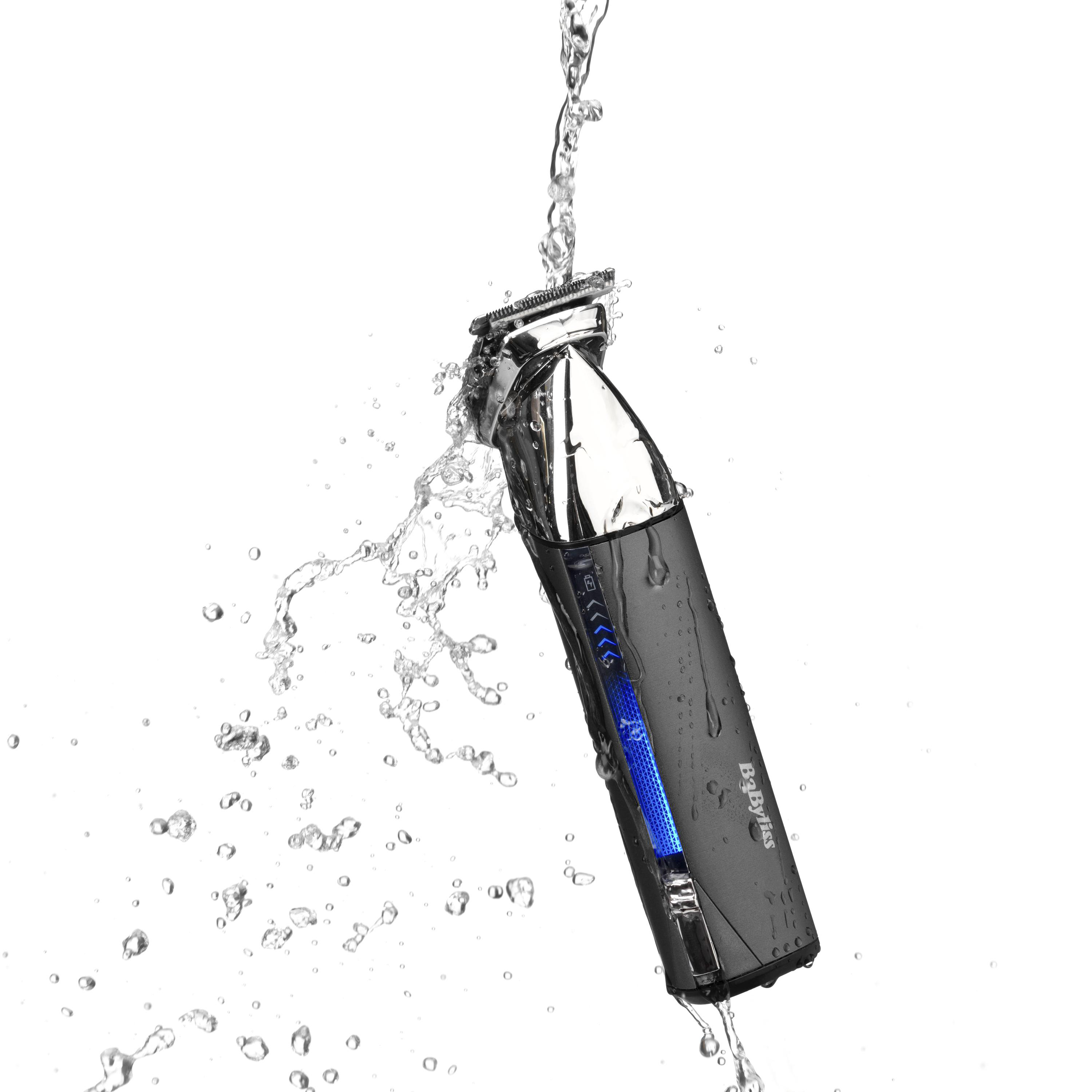 Haarschneider unter einem Wasserstrahl, der Wassertropfen zeigt. Der Rasierer ist grau.