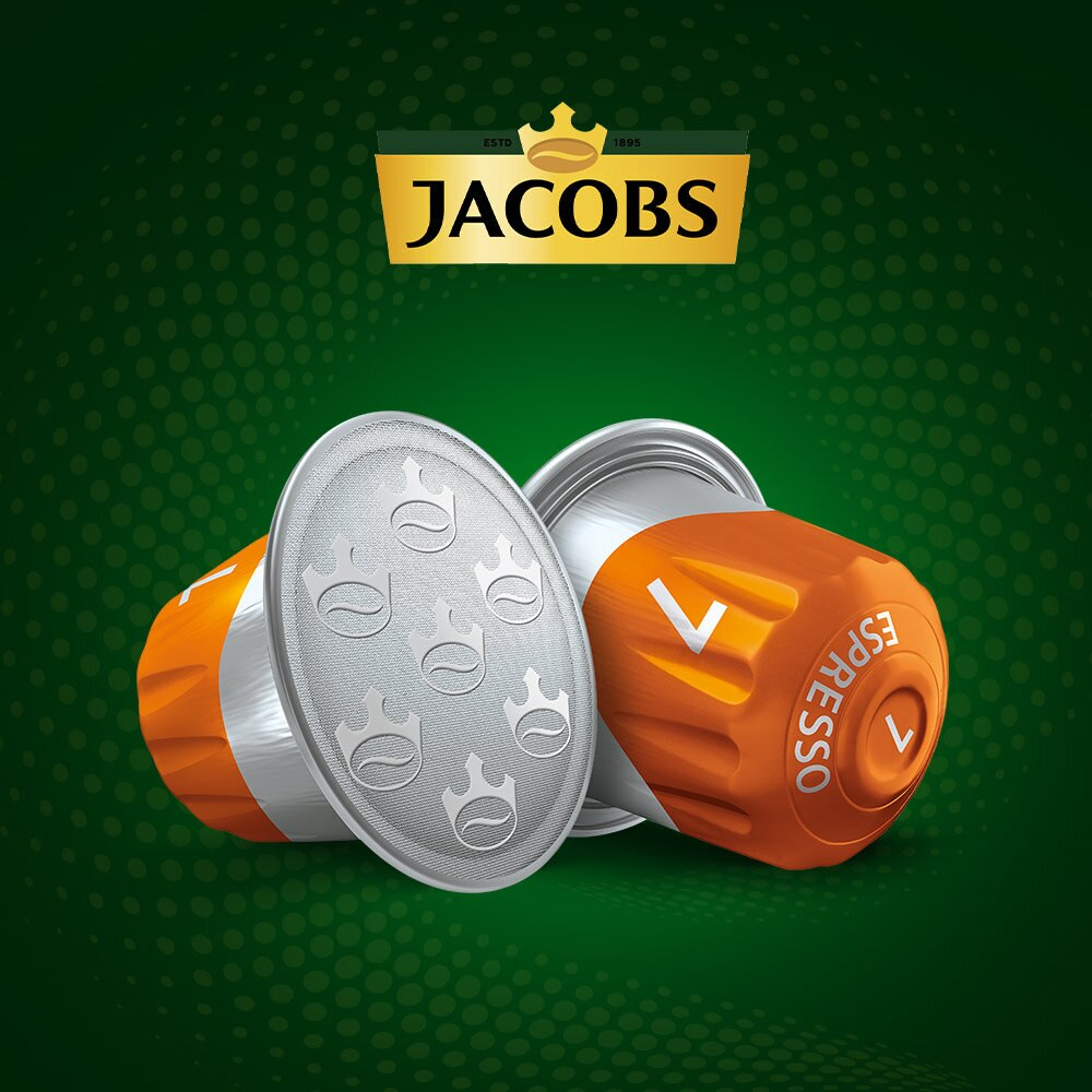 Dwie kapsułki do kawy espresso w pomarańczowo-srebrnej kolorystyce, zielone tło.