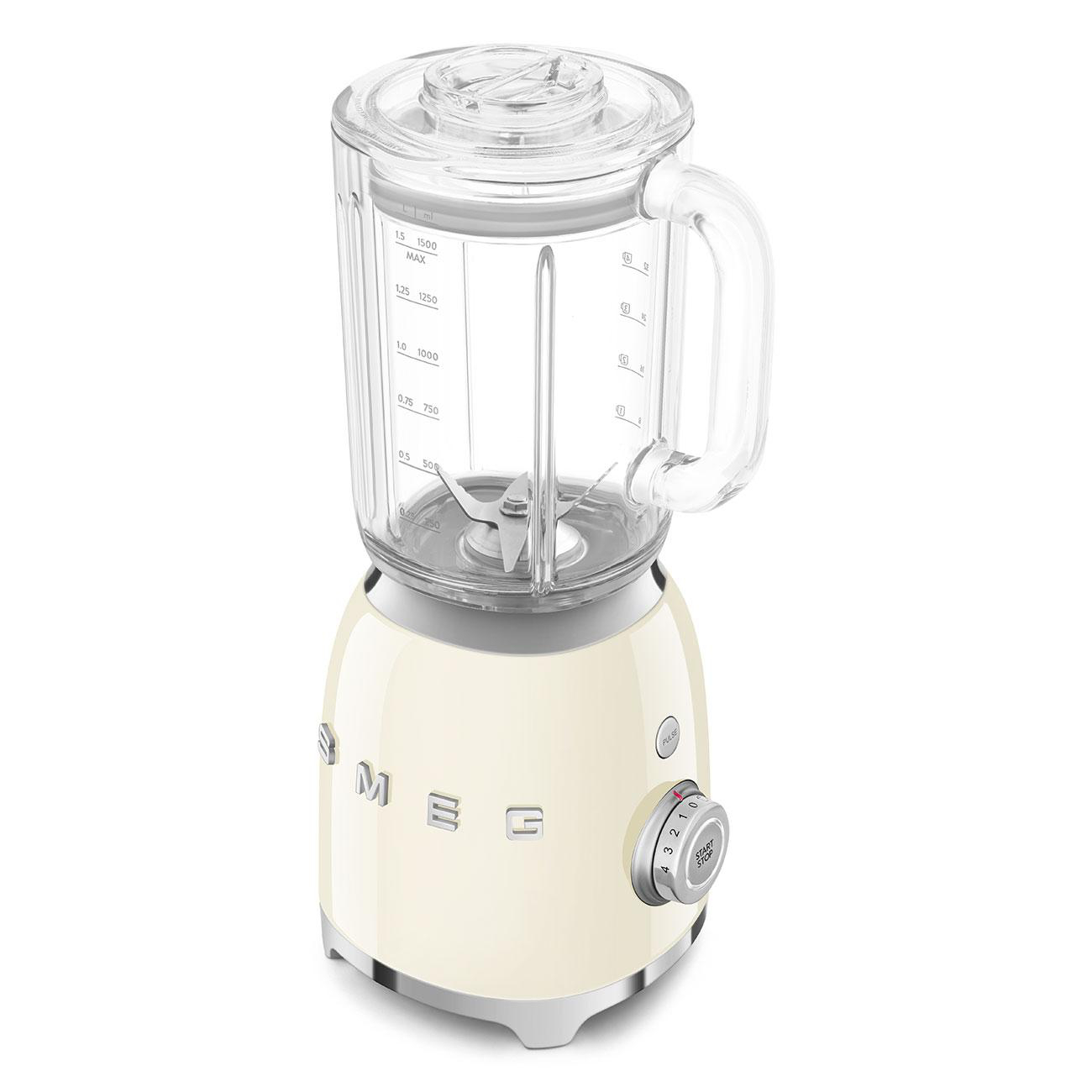 Ein cremefarbener Mixer mit einem Glasbehälter, einem Griff und einem Drehregler. Er steht auf einer weißen Oberfläche.