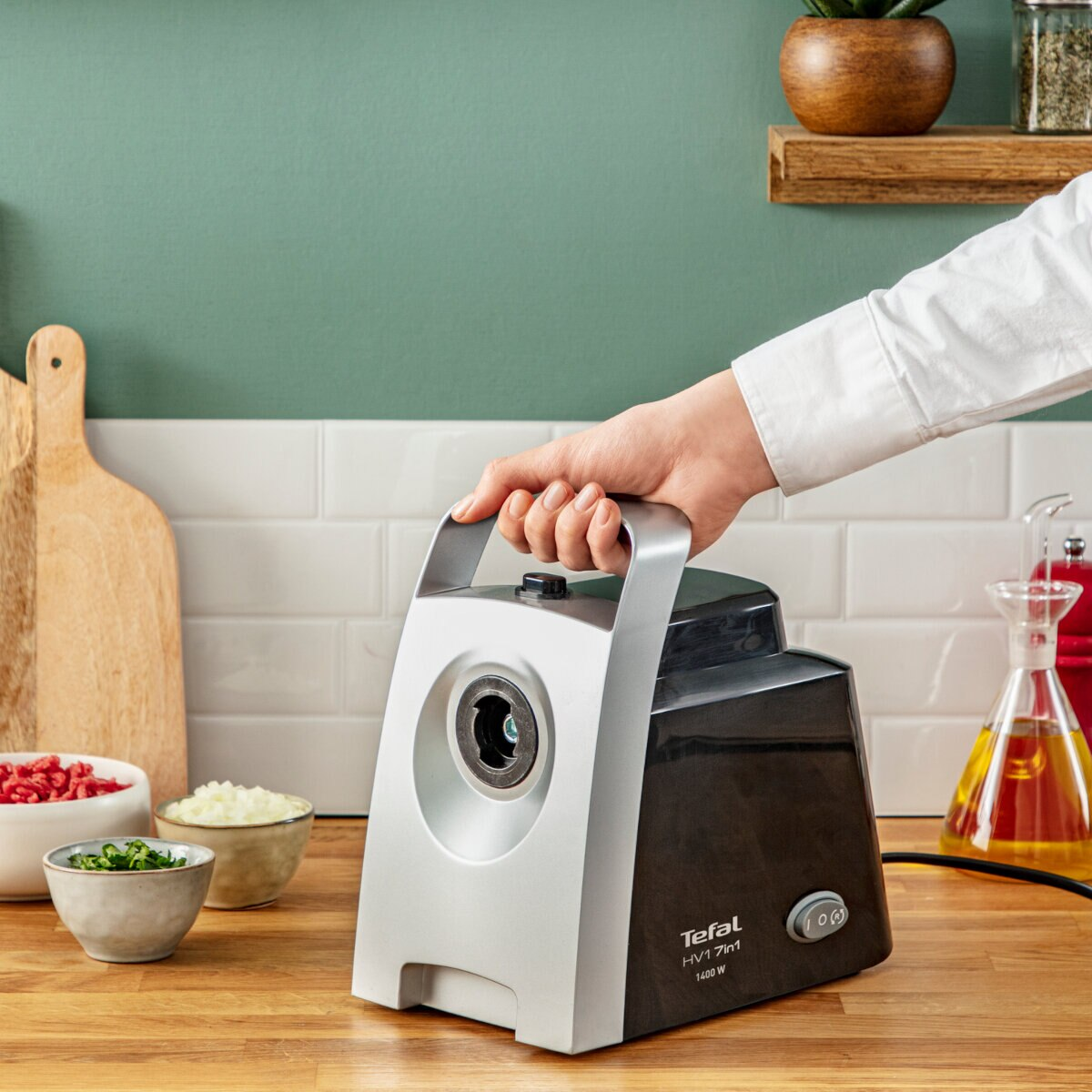 Osoba trzymająca czarno-srebrną maszynkę do mięsa z składnikami.