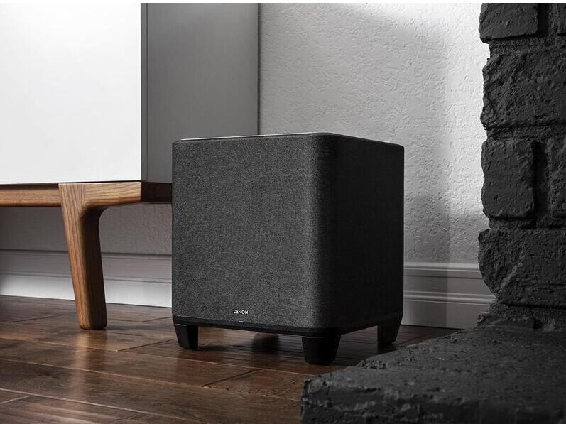 Czarny subwoofer na drewnianej podłodze.