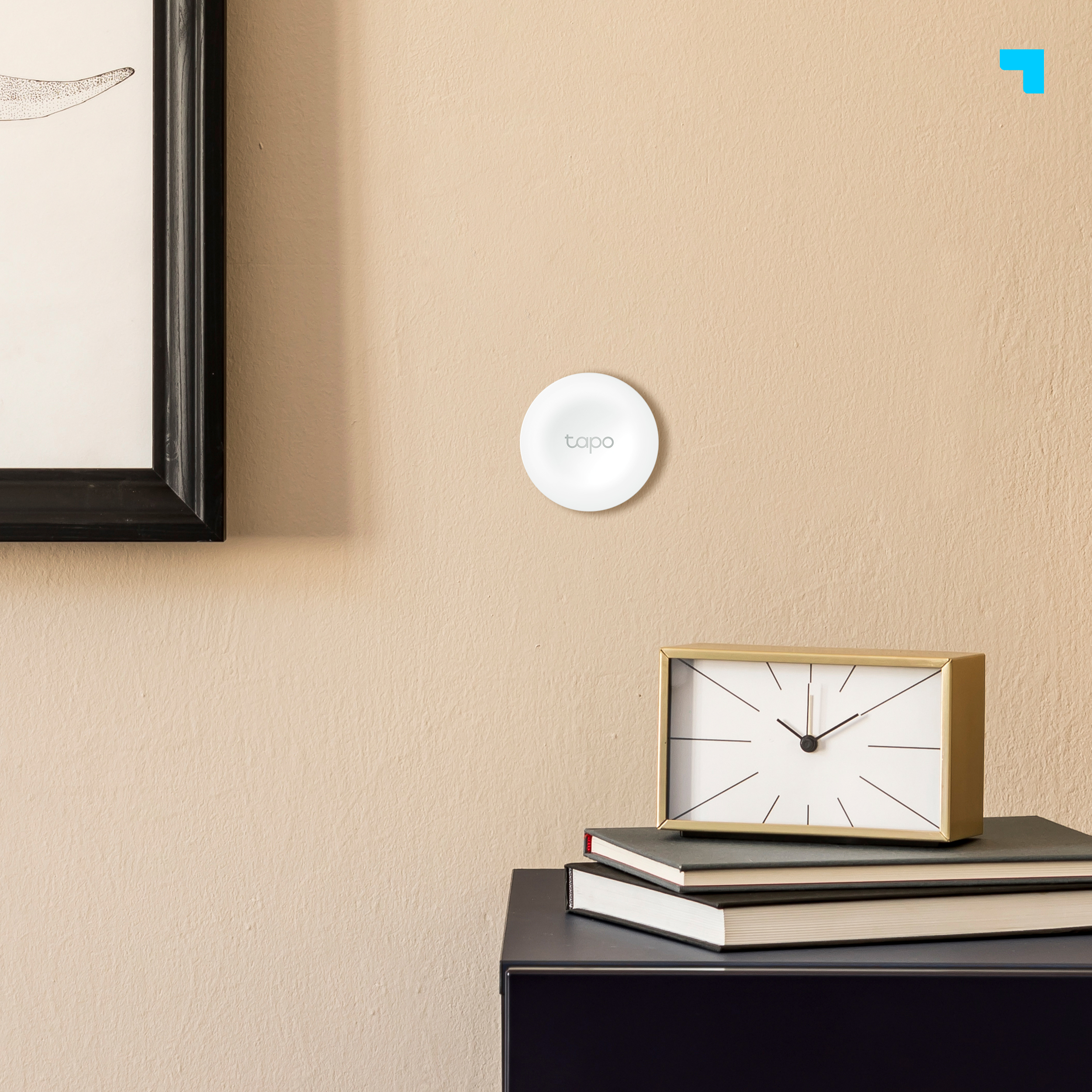Dispositivo montado en la pared con reloj y libros sobre una mesa oscura.