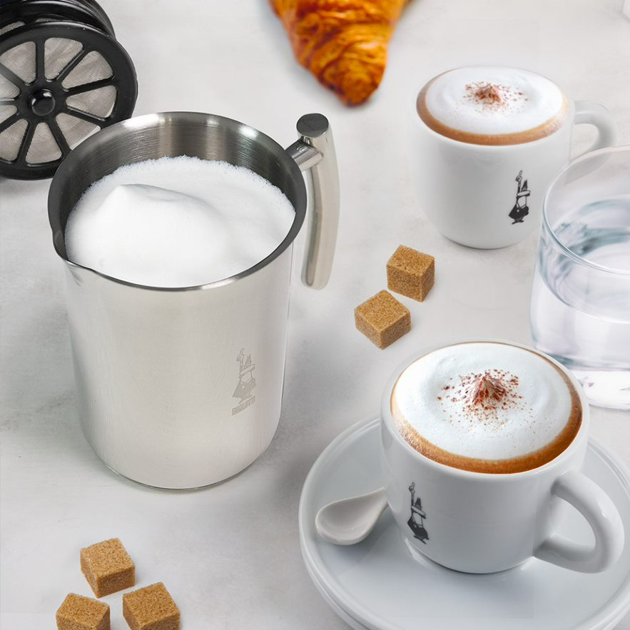 Ezüst tejhabosító, két csésze cappuccino és barna cukorkockák.