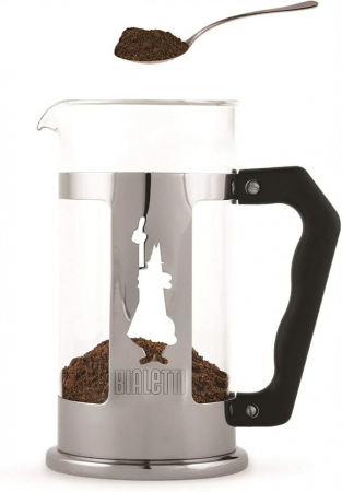 Egy Bialetti French press kávéfőző, tele kávézacczal. Egy kanál zacc lebeg felette.