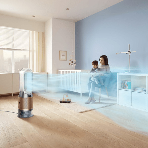 Een vrouw die een baby vasthoudt in een kamer met een luchtreiniger.