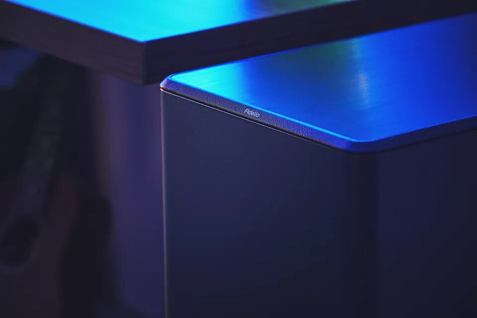 Ciemnoniebieskie urządzenie ze słowem "Fidelio". Zbliżenie, drewniany stół.