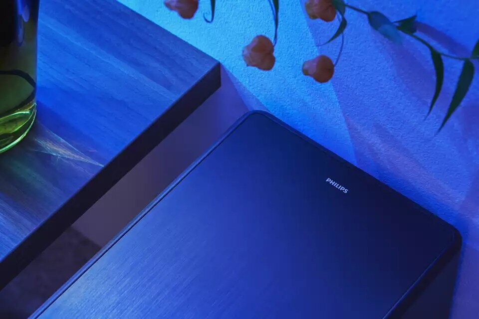 Ciemnoniebieski tablet z logo Philips na niebiesko oświetlonej powierzchni.