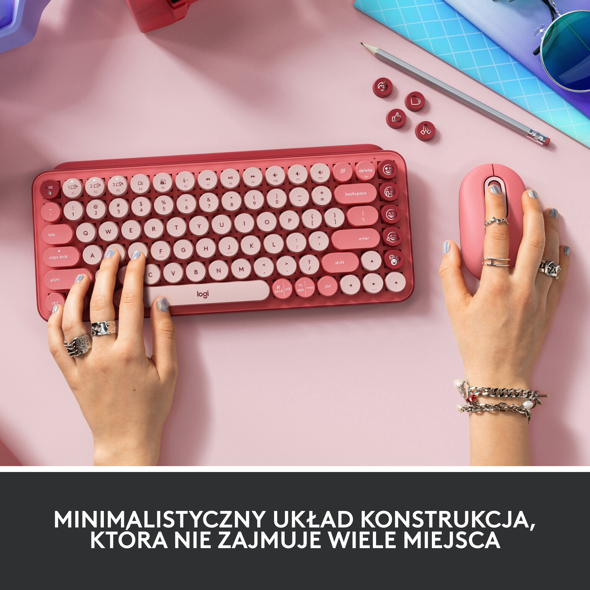 Ręce piszące na czerwonej klawiaturze z różową myszą, na różowej powierzchni, widok z góry.