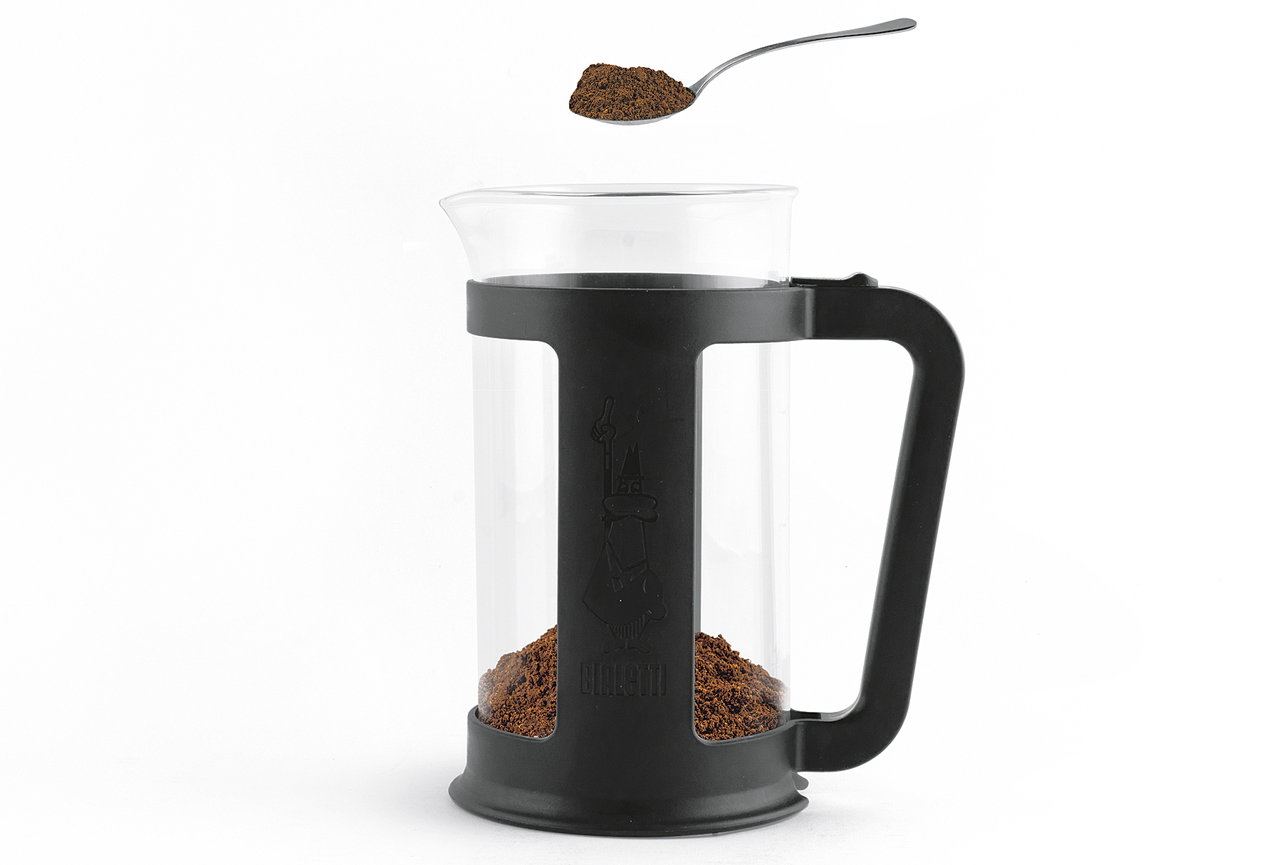 Egy French press kávéfőző őrölt kávéval és egy kanállal, ami több kávét tart.