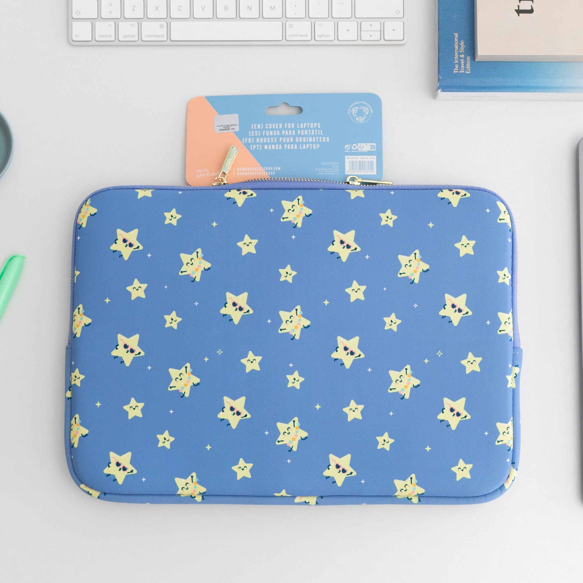 Funda azul para portátil con estrellas y teclado al fondo.