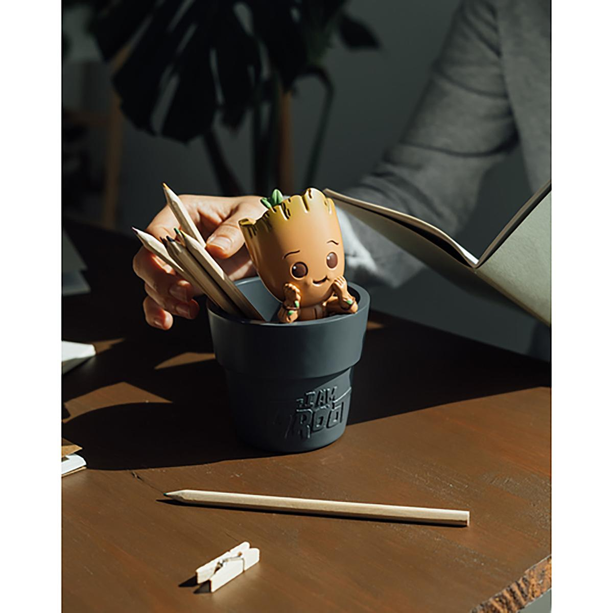 Groot-Figur mit Bleistiften in einem Topf auf einem Holztisch.