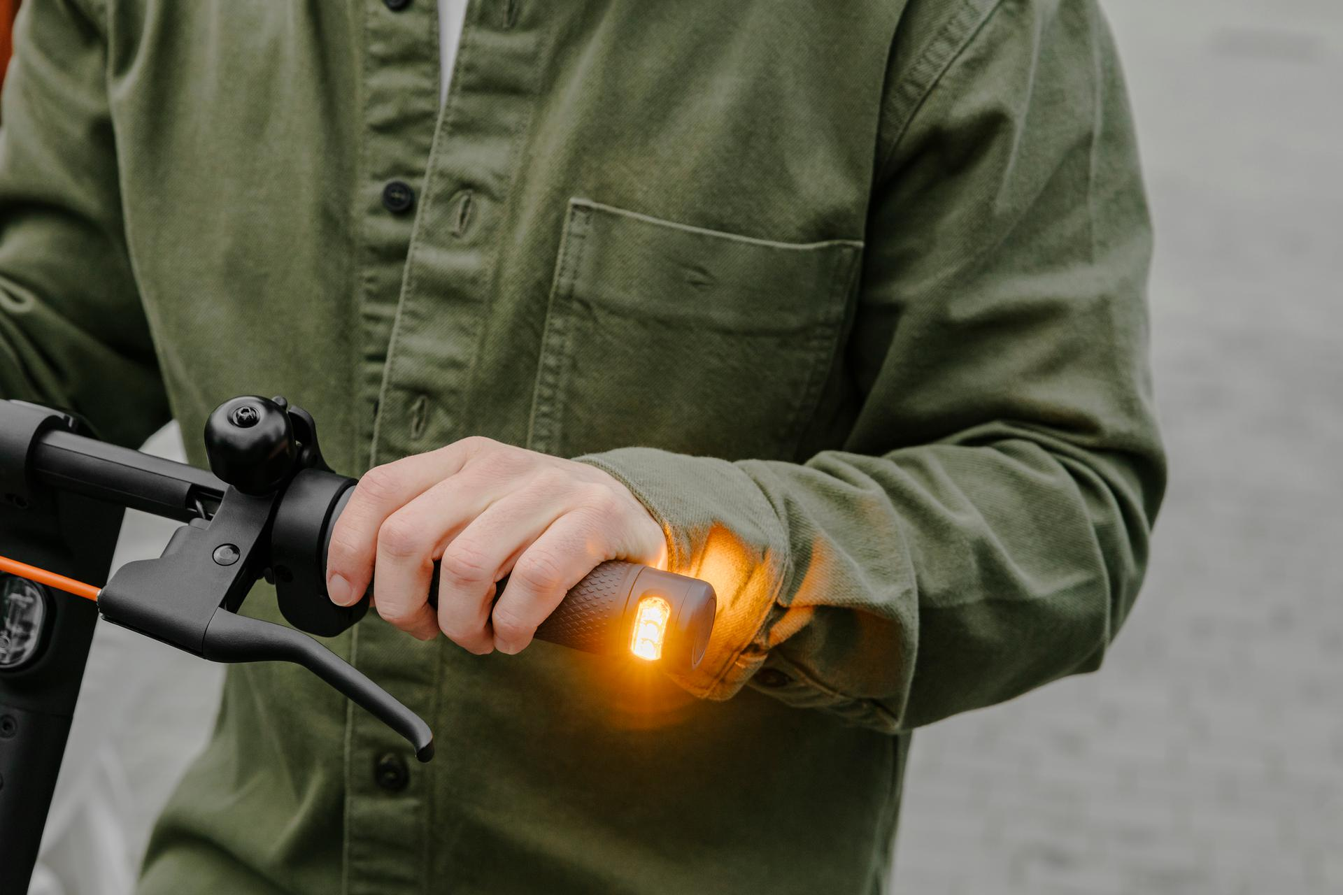 Person hält den Lenker eines Elektrorollers. Hand ist auf der rechten Seite.