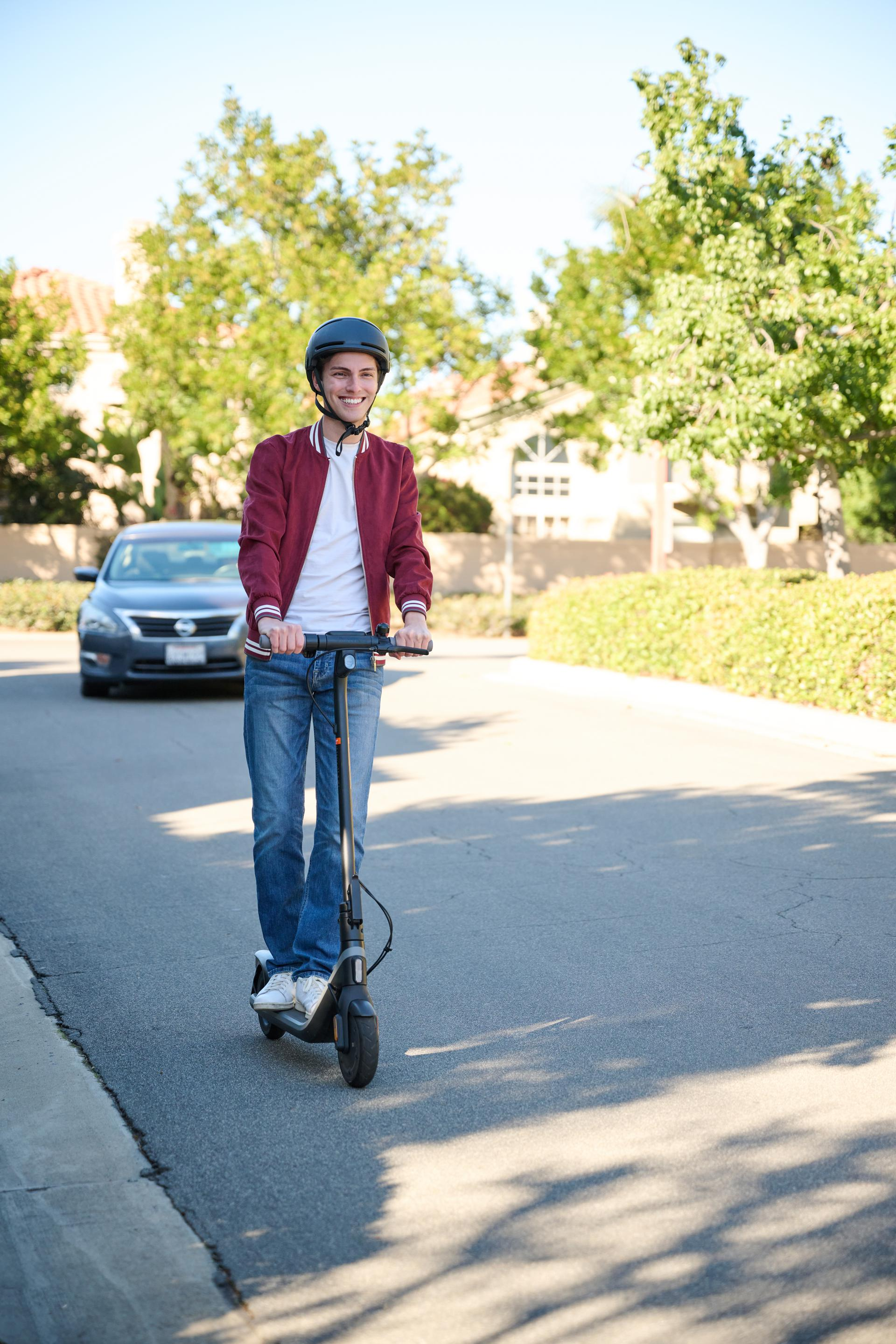 Hombre con casco monta un patinete eléctrico.