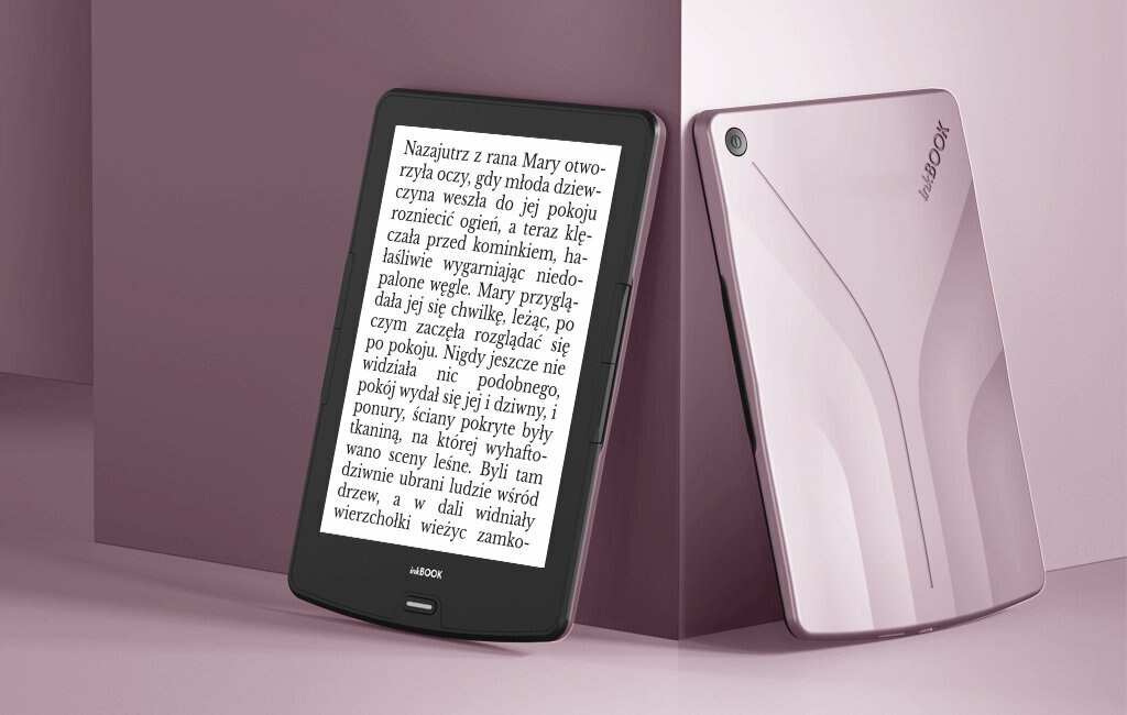 Dwa czytniki e-booków, jeden otwarty, jeden zamknięty, na różowej powierzchni. Tekst widoczny na ekranie.
