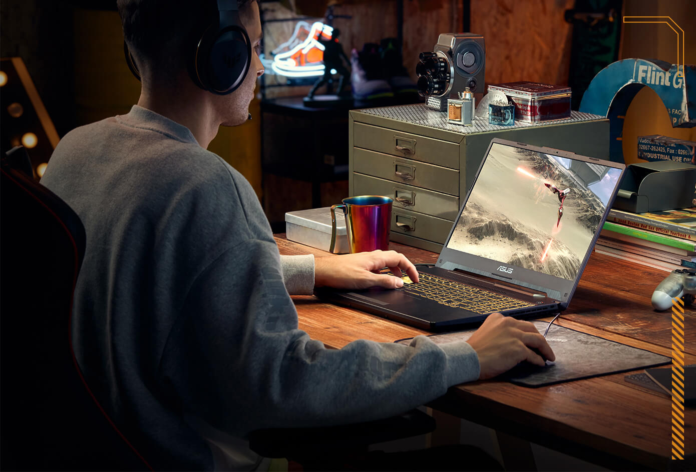 Férfi laptopon játszik. A képernyő egy játékjelenetet mutat. Egy asztal kiegészítőkkel.