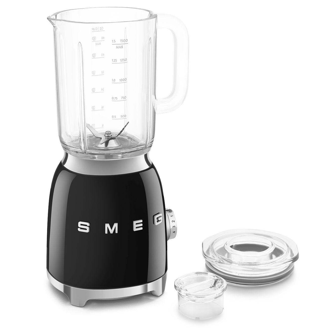 Ein schwarzer und silberner Smeg-Mixer mit Glaskrug, Deckel und kleinem Messbecher steht auf weißem Untergrund.