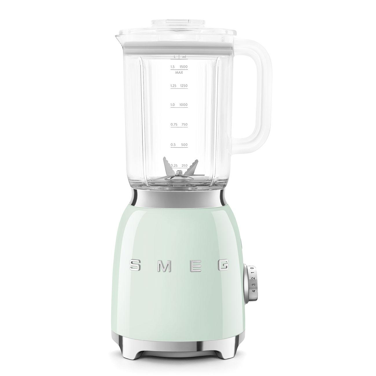 Minzgrüner SMEG-Mixer mit Glasbehälter und weißem Deckel auf weißer Fläche.