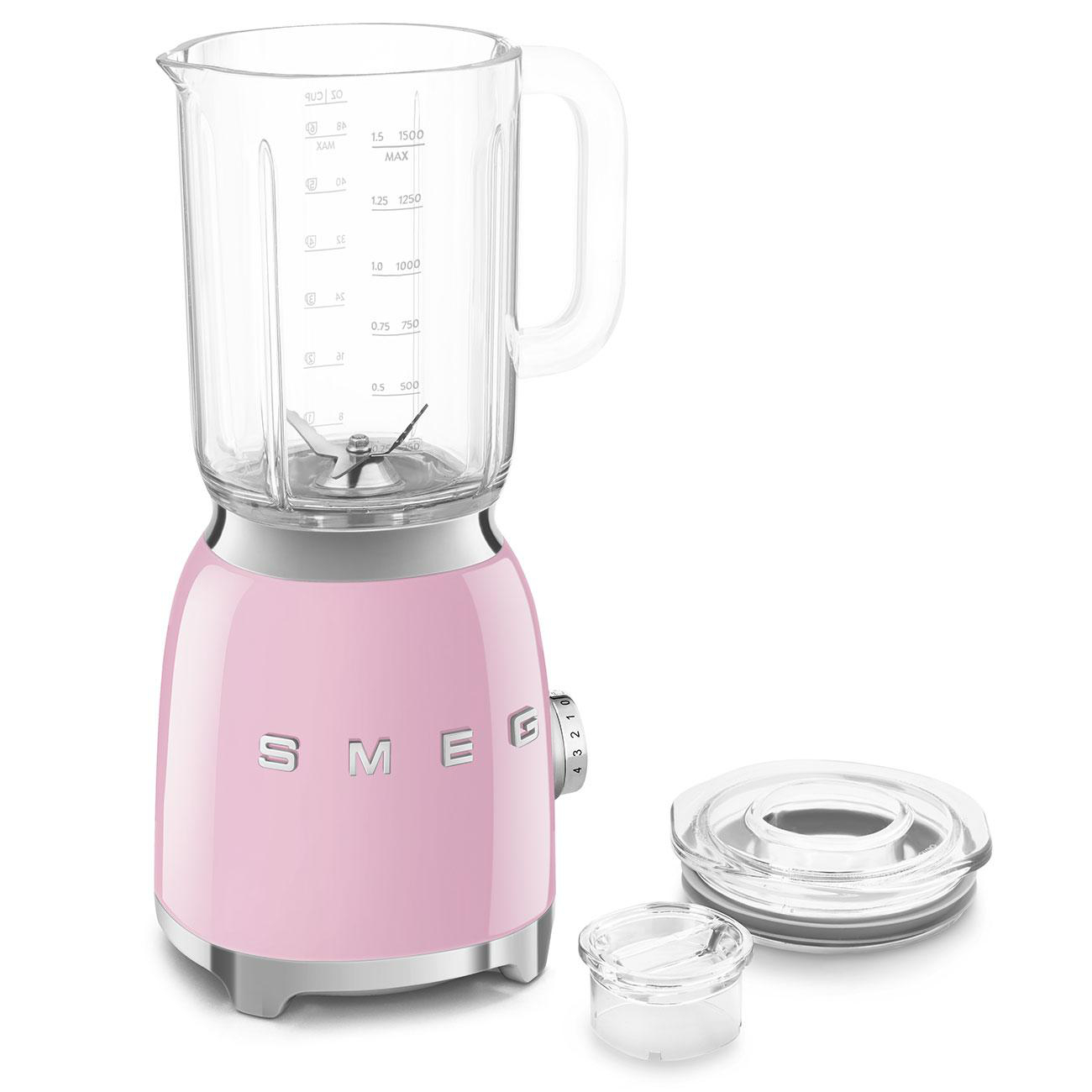 Pinker Smeg-Mixer mit Glasbehälter, Deckel und kleinem Becher auf weißem Hintergrund.