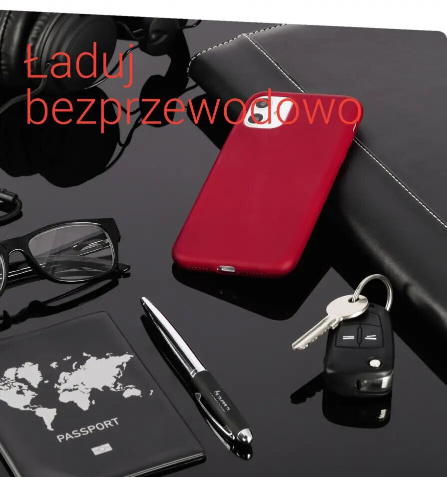 Biurko z czerwoną obudową telefonu, okularami, paszportem, długopisem, kluczami i słuchawkami. Czarna powierzchnia.