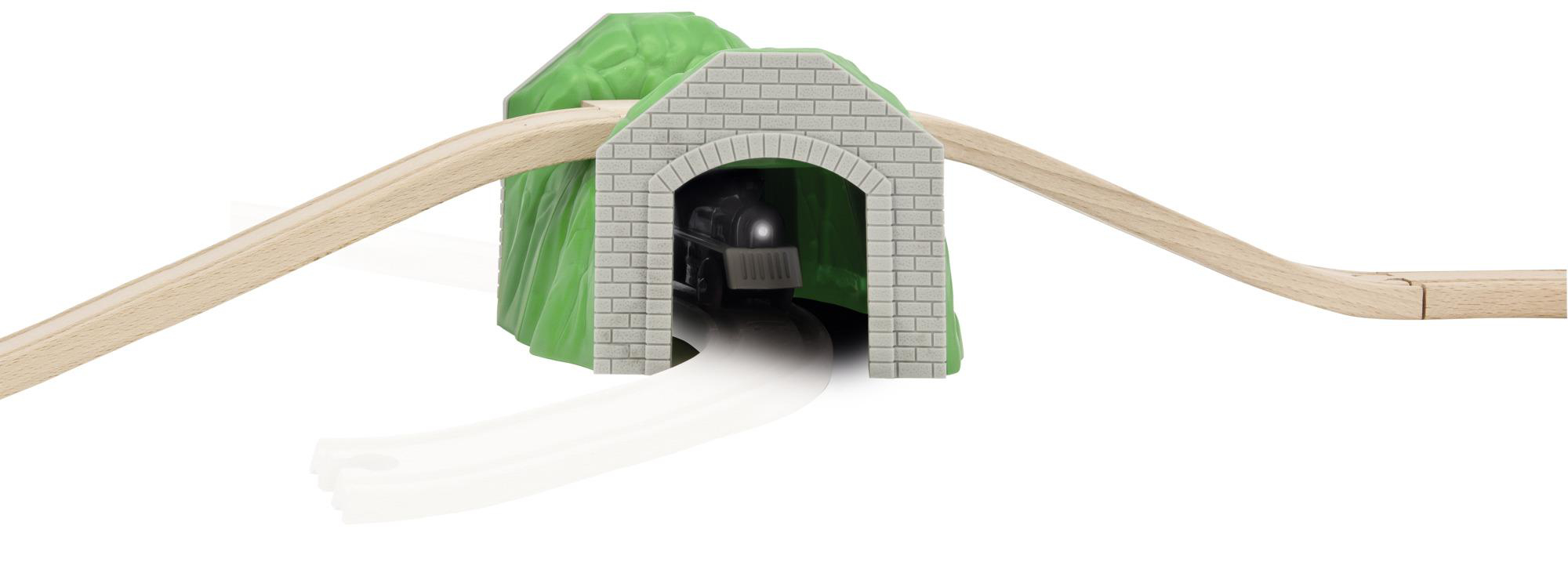 Spielzeugzug, der in einen Tunnel einfährt, Zuggleise führen durch einen grünen Hügeltunnel auf weißem Hintergrund.