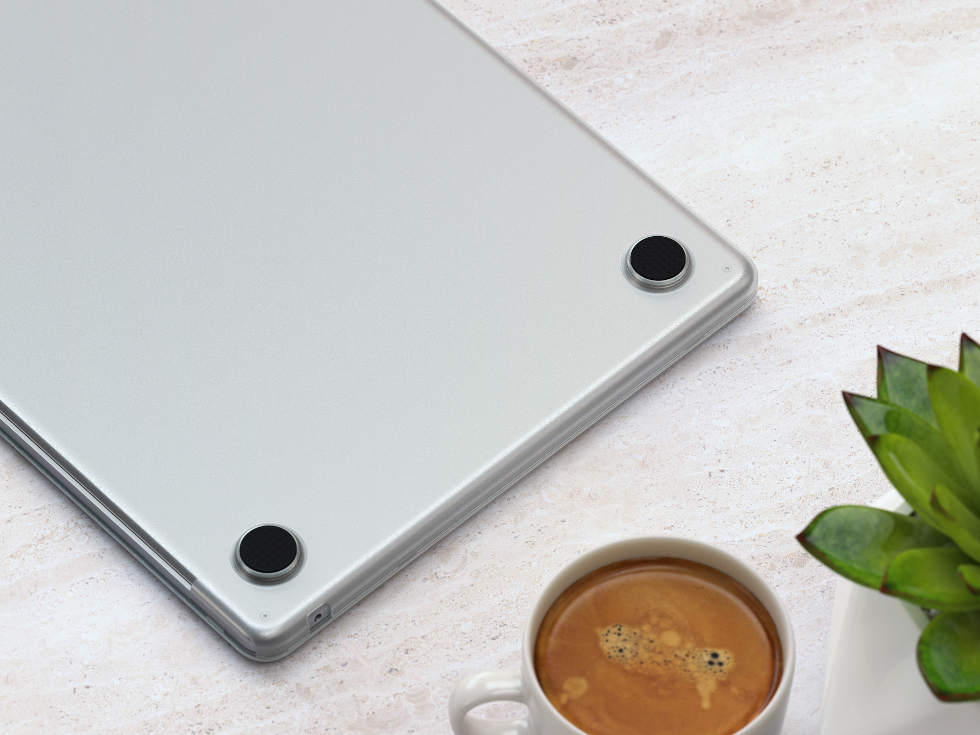 Base per tablet argentata con due piedini circolari neri, con tazza e pianta nel fotogramma.