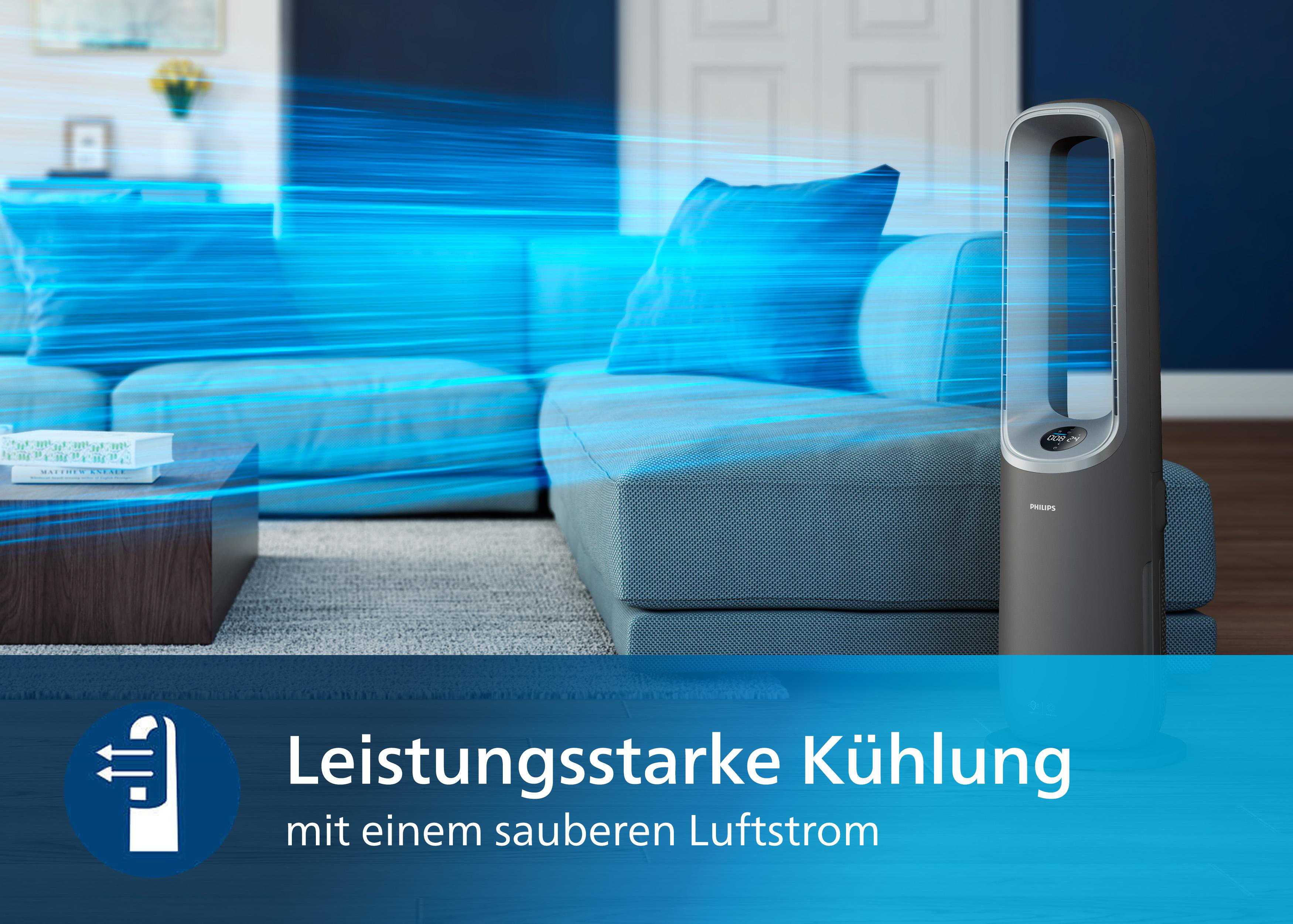 Ein dunkelgrauer Ventilator steht auf einem Holzboden. Der Ventilator steht vor einem blauen Sofa.