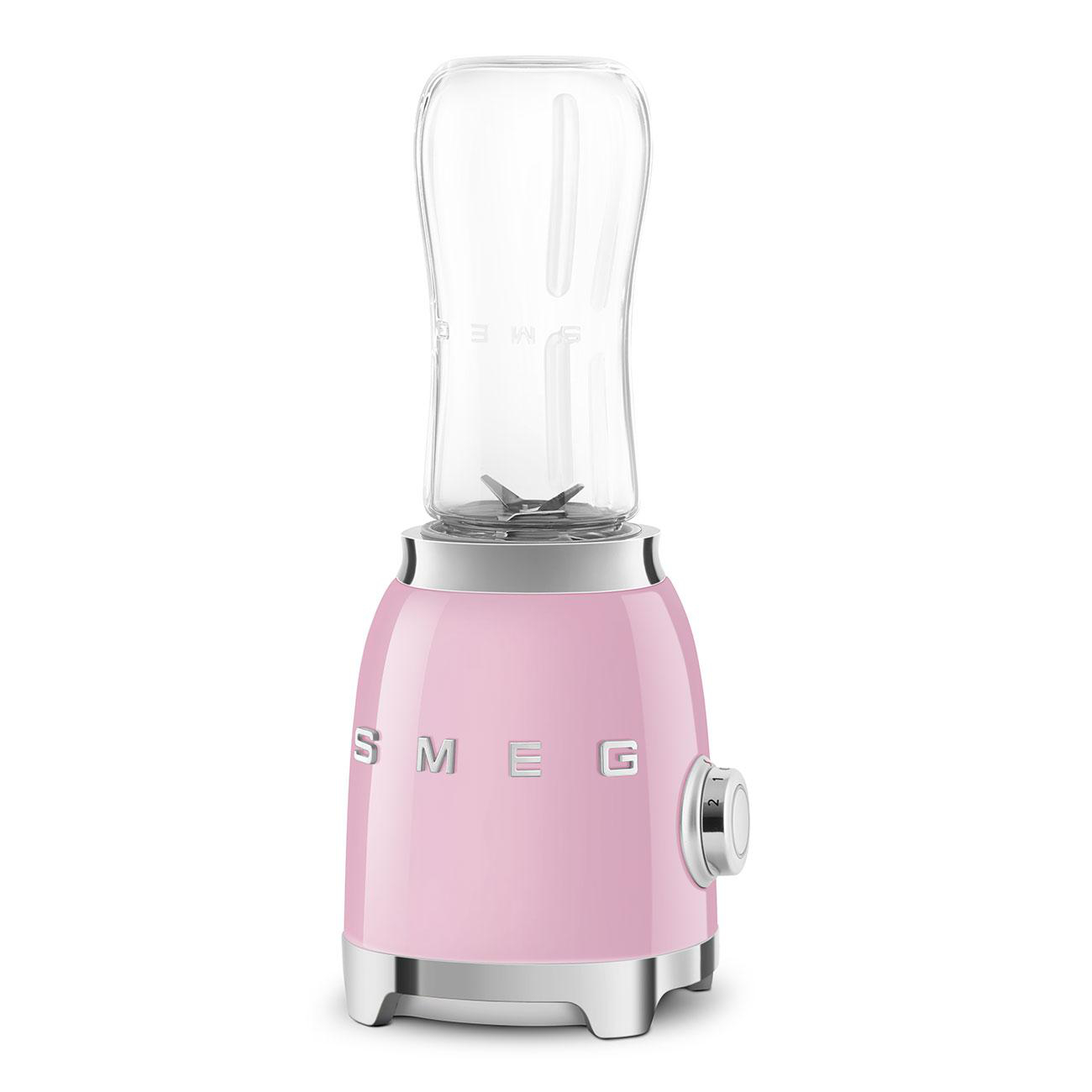 Rosa Smeg-Mixer mit einem transparenten Glasbehälter auf weißer Oberfläche. Es hat einen Knopf.