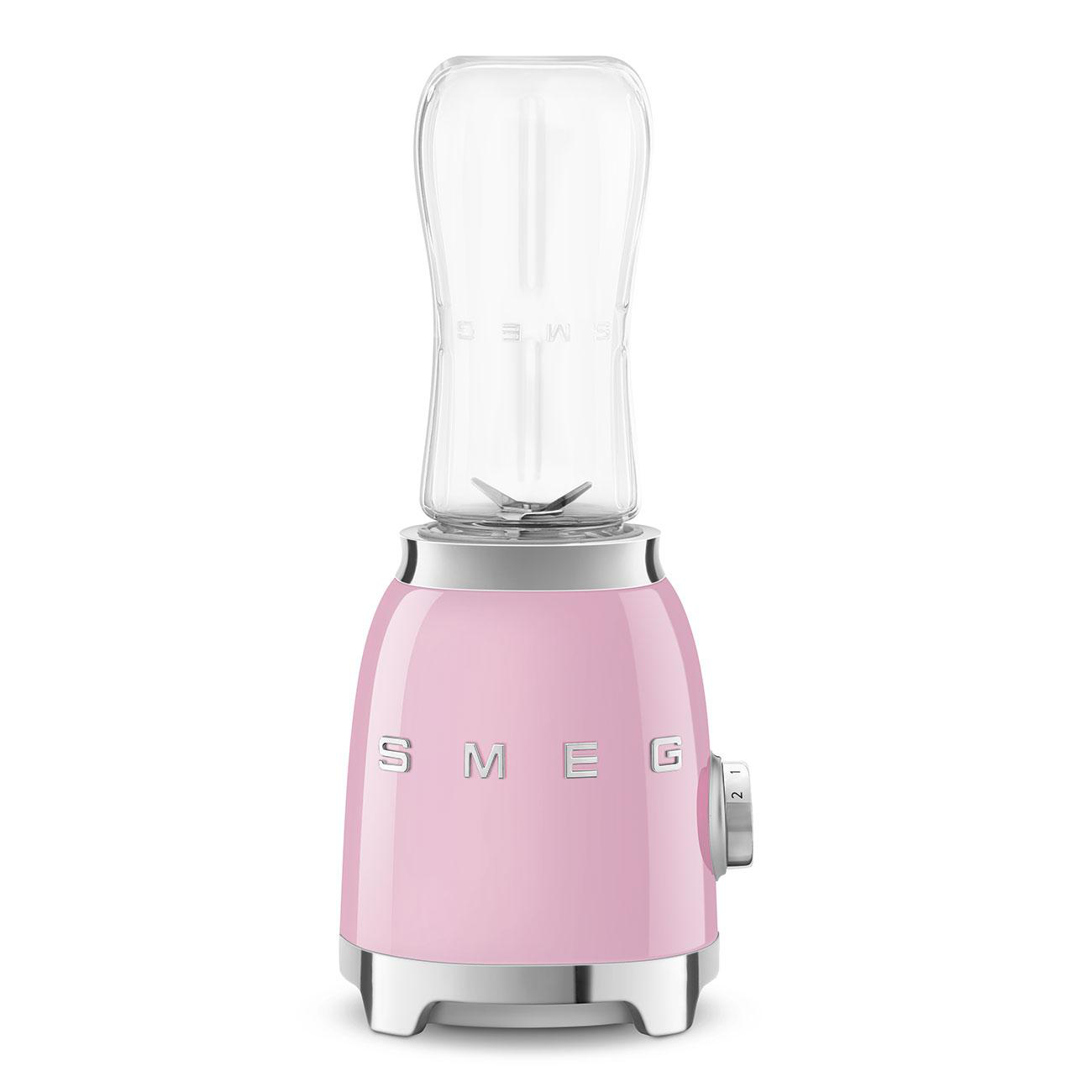 Ein pinkfarbener SMEG-Mixer mit einem durchsichtigen Glasaufsatz. Der Sockel hat einen Drehknopf und silberne Akzente. Weißer Hintergrund.