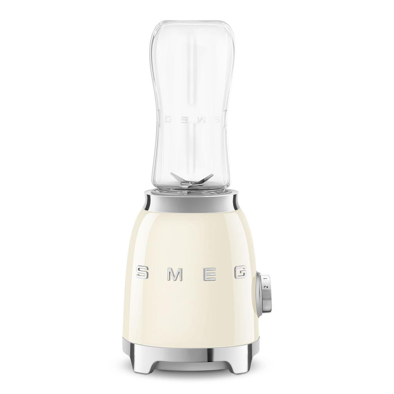 Ein cremefarbener Smeg-Mixer mit transparentem Behälter. Mit silbernem Sockel und Drehknopf.