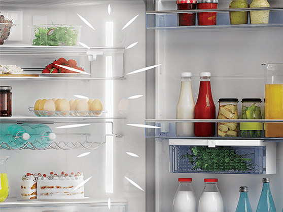 Intérieur d'un réfrigérateur avec des aliments sur les étagères. Contient fruits, légumes, boissons et desserts.