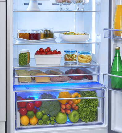 Intérieur du réfrigérateur. Étagères avec bocaux, fruits et légumes. Les tiroirs ont des lumières bleues.
