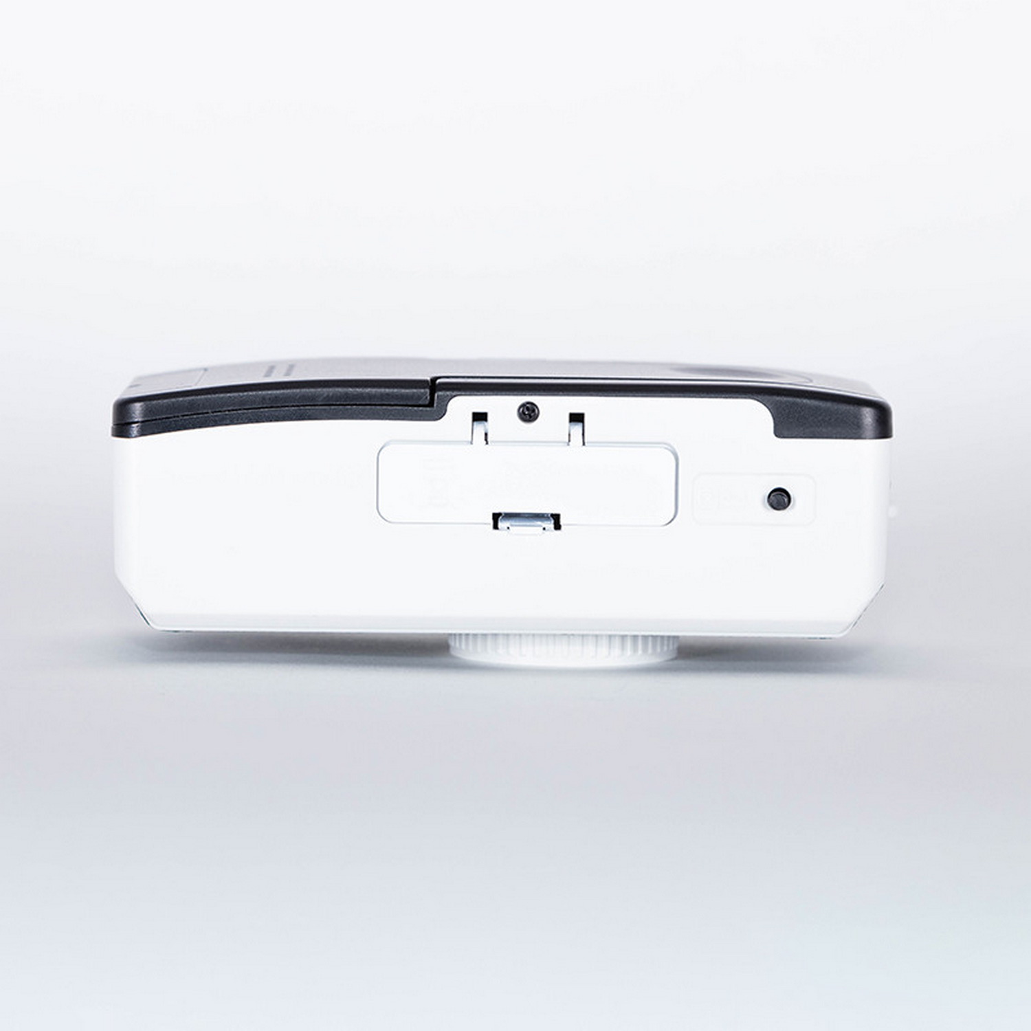 A white device with a black top, a USB port, and a circular base.