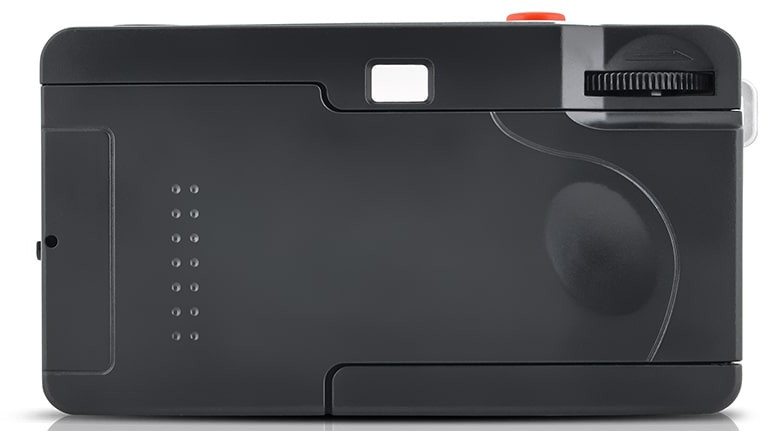 Black camera with a red button and a dial. It sits on a white surface.