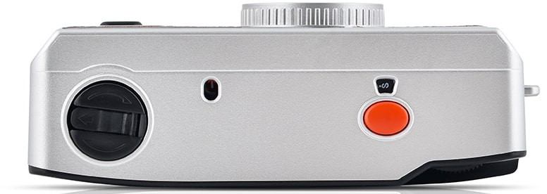 Silver camera side view. Black dial and button, red button. Top dial.