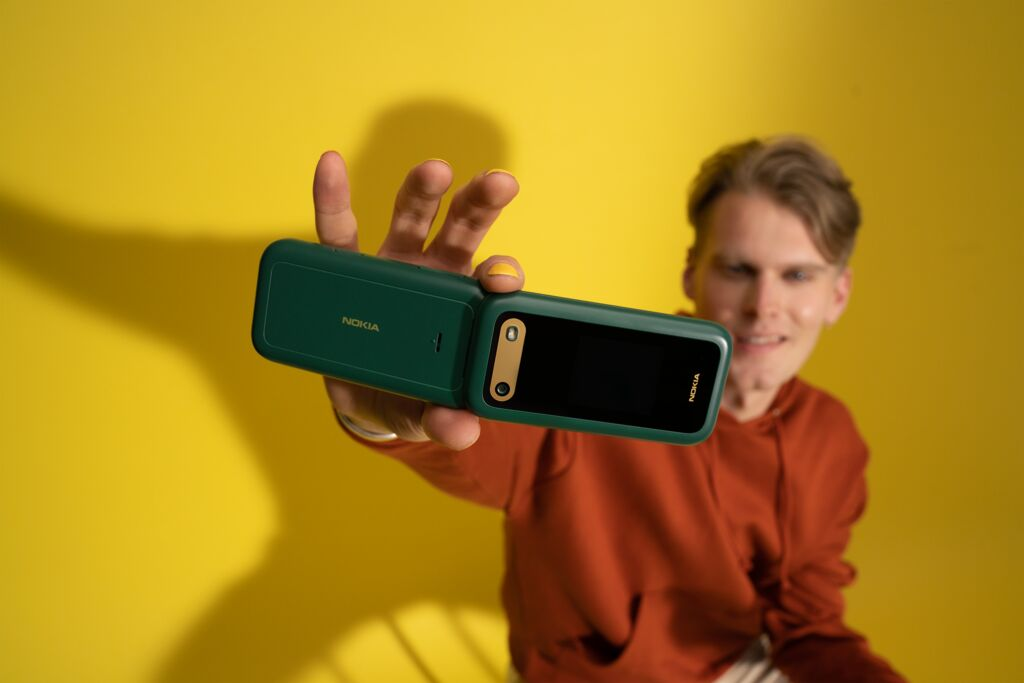 Férfi tart egy nyitott, sötétzöld Nokia kagylót, a kamerára mosolyogva.