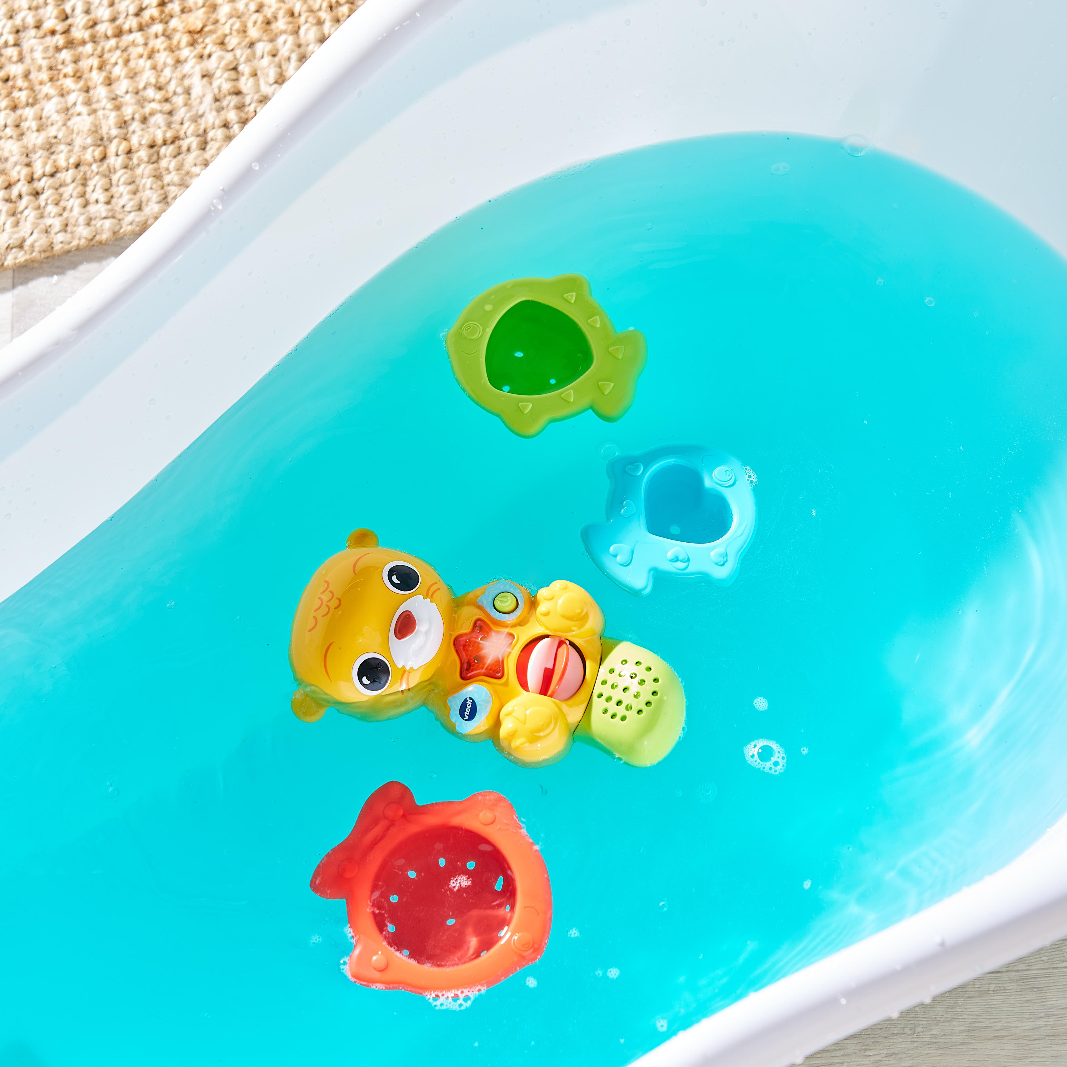 Ein gelber Spielzeugfisch, ein grüner Fisch, ein blauer Fisch in einer Badewanne mit blauem Wasser.
