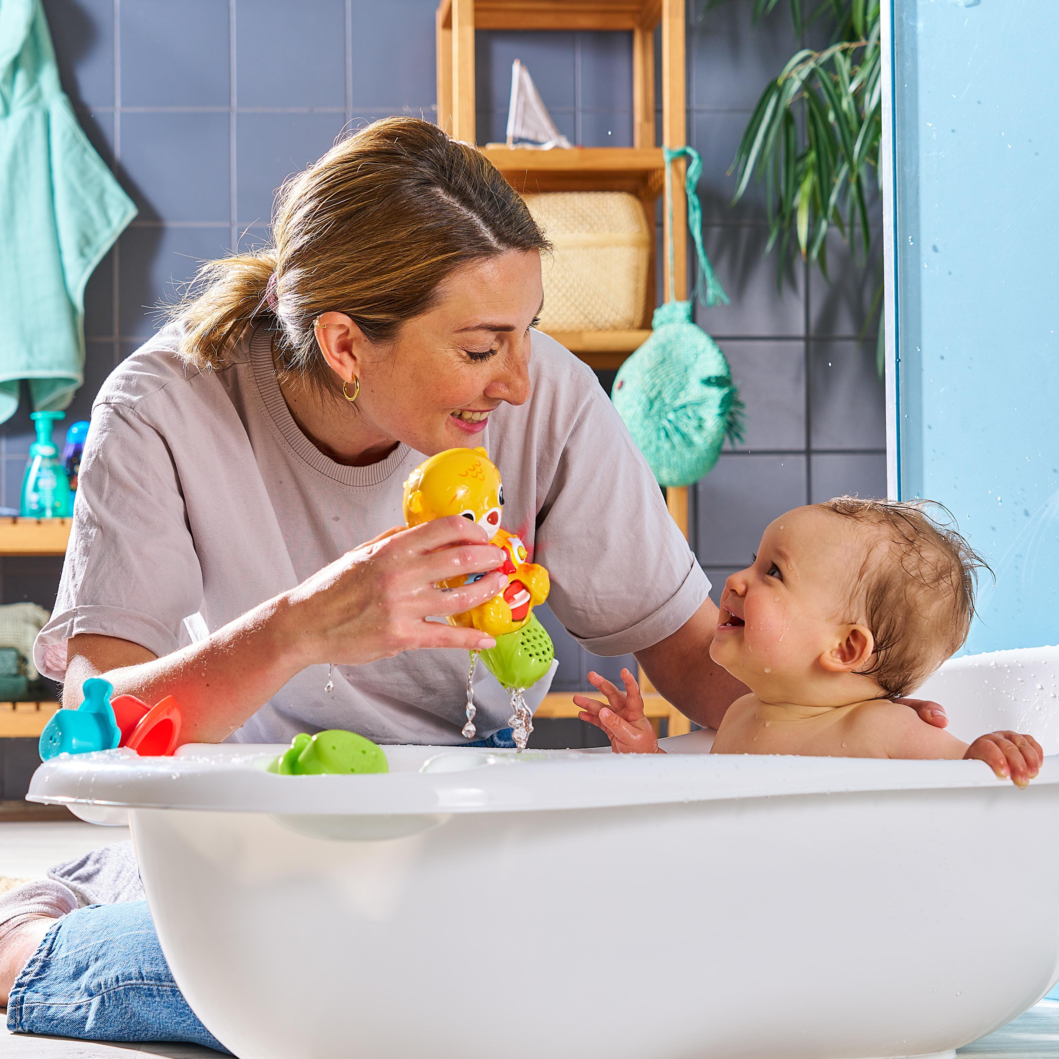 Mutter und Baby in einer Badewanne, die mit Badespielzeug spielen.