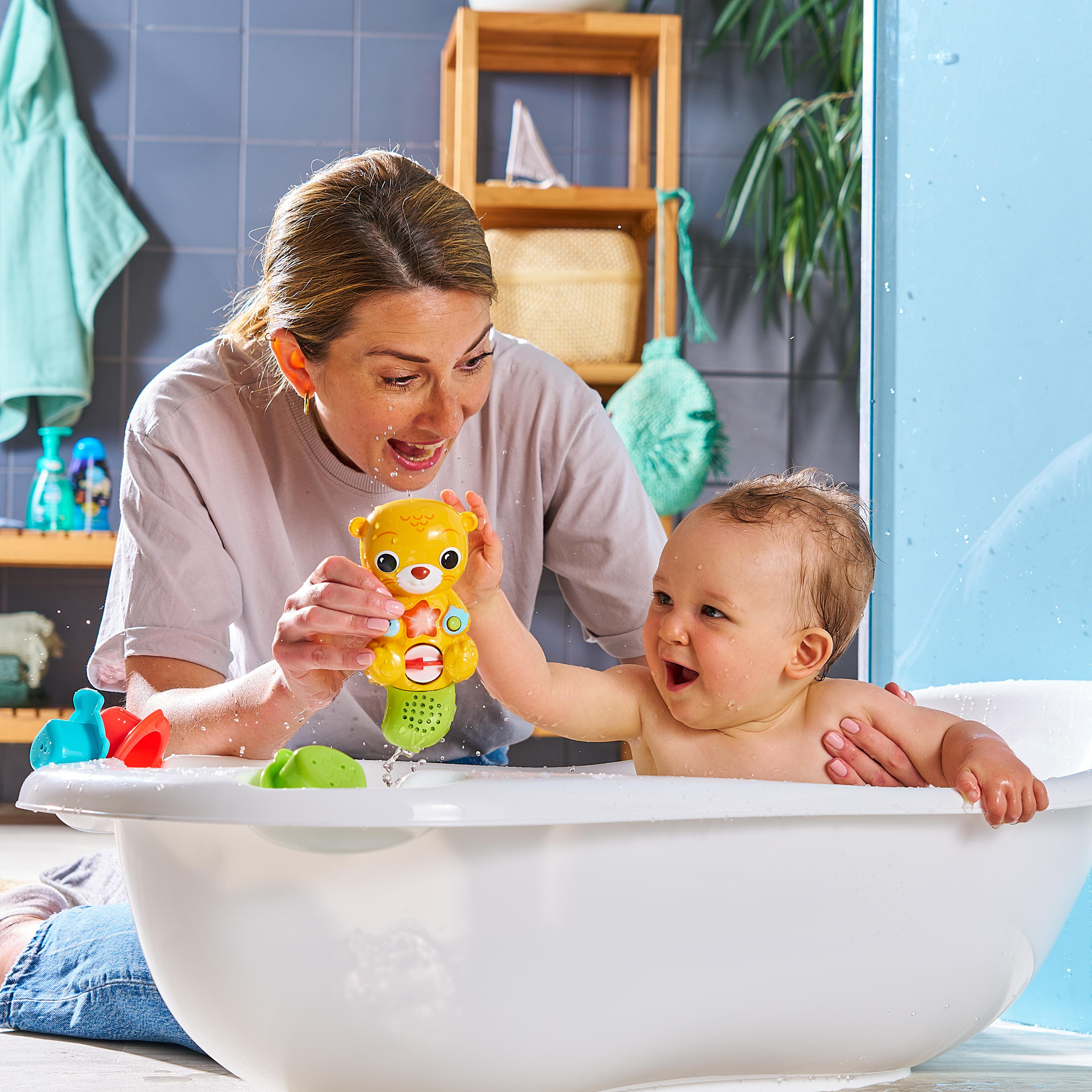 Frau und Baby in einer Badewanne, die mit einem gelben Spielzeug spielen. Blaues und weißes Badezimmer.